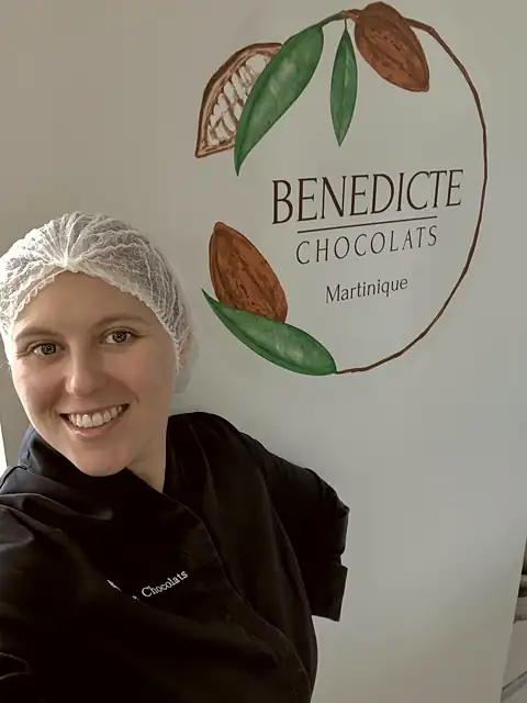 Bénédicte dans son atelier aujourd'hui, devant le logo Bénédicte Chocolats